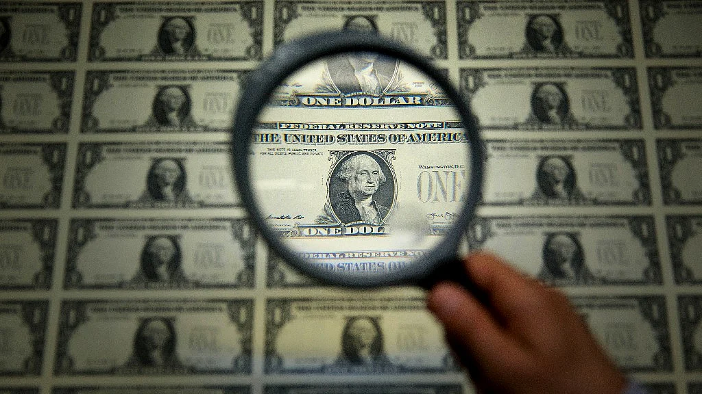 A magnifying glass is held over a one dollar note sheet in Washington, D.C., U.S. (Photographer: Andrew Harrer/Bloomberg)