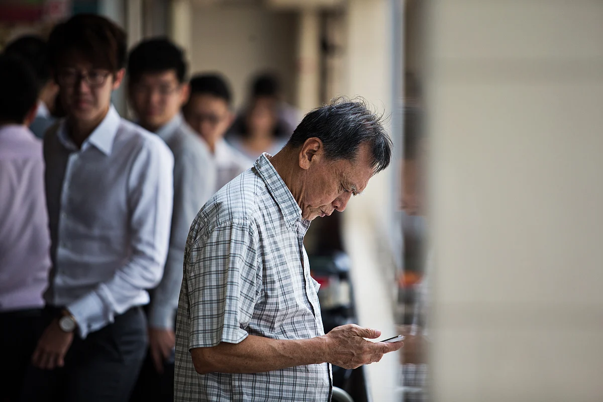 A man uses a mobile phone at the Golden Shoe food center at Raffles Place in Singapore. (Photographer: Nicky Loh/Boomberg)