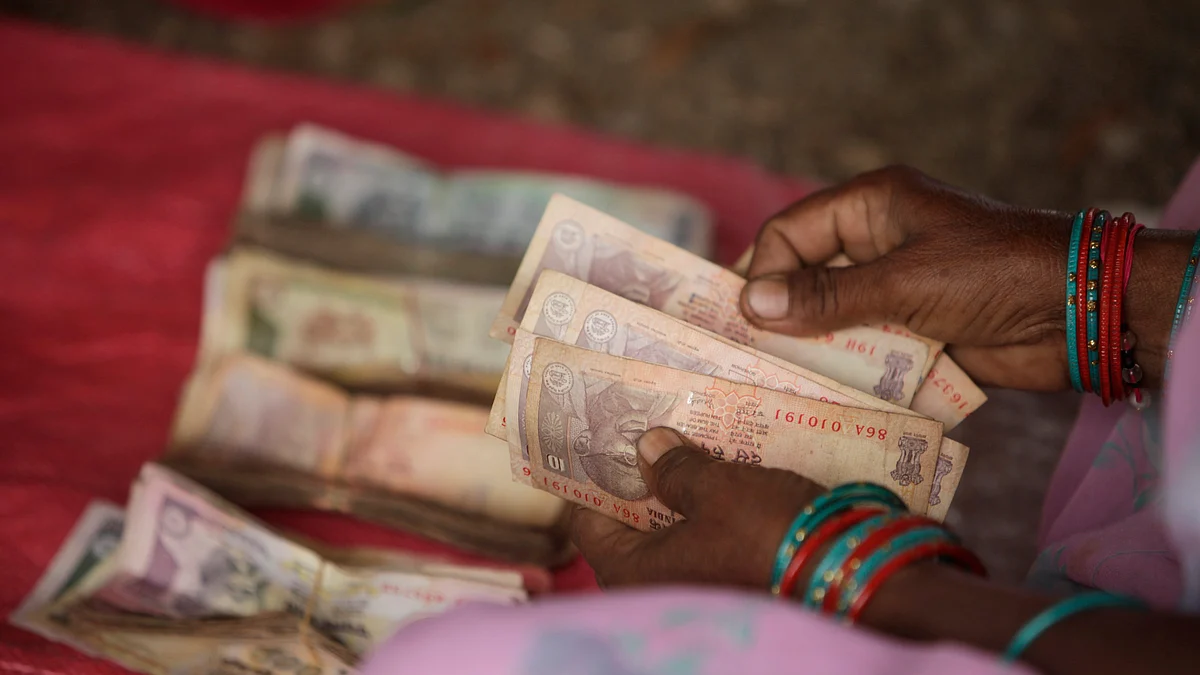 A “centre leader” counts money to be distributed as a micro-loan at a meeting organized by a microfinance institution in Sadasivpet, India. (Photographer: Adeel Halim/Bloomberg)