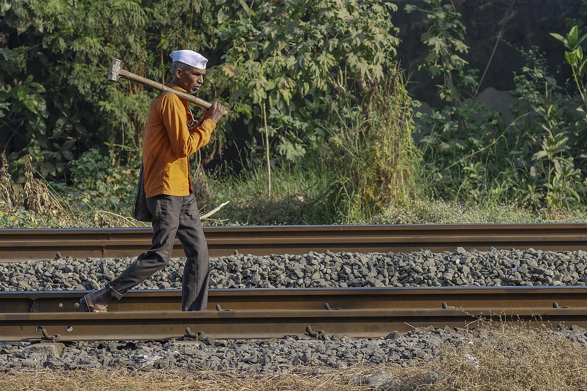 A worker carries a sledgehammer as he walks along rail tracks in Mumbai. (Photographer: Dhiraj Singh/Bloomberg)