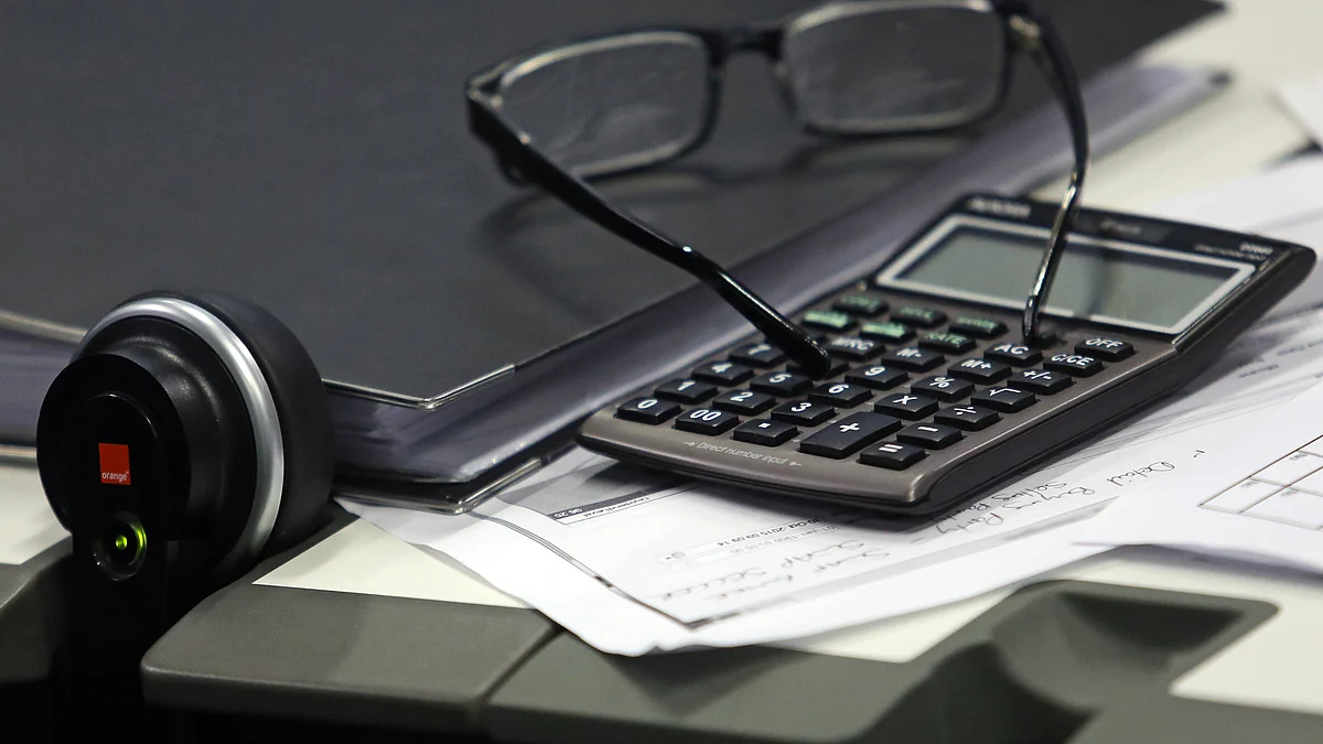A fixed line telephone and a calculator sit next to a pair of spectacles. (Photographer: Chris Ratcliffe/Bloomberg)