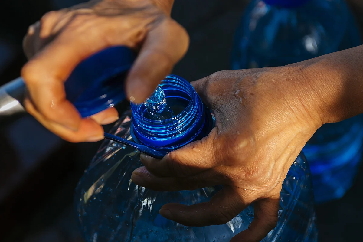 A resident fills a plastic bottle (Photographer: Waldo Swiegers/Bloomberg)