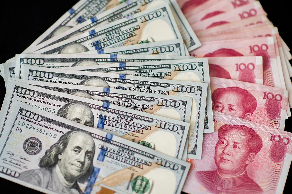 U.S. one-hundred dollar bills and Chinese one-hundred yuan banknotes are arranged for a photograph in Hong Kong, China. (Photographer: Xaume Olleros/Bloomberg)