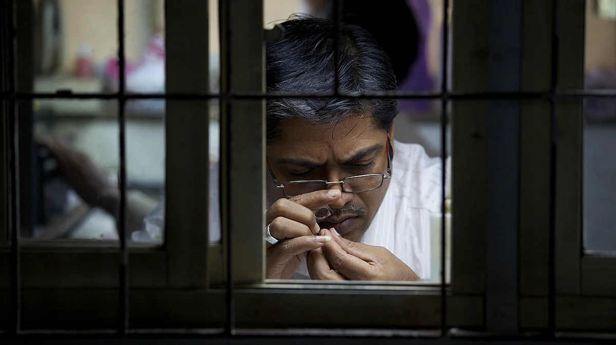 A worker checks a diamond through a magnifying glass. (Photographer: Adeel Halim/Bloomberg)