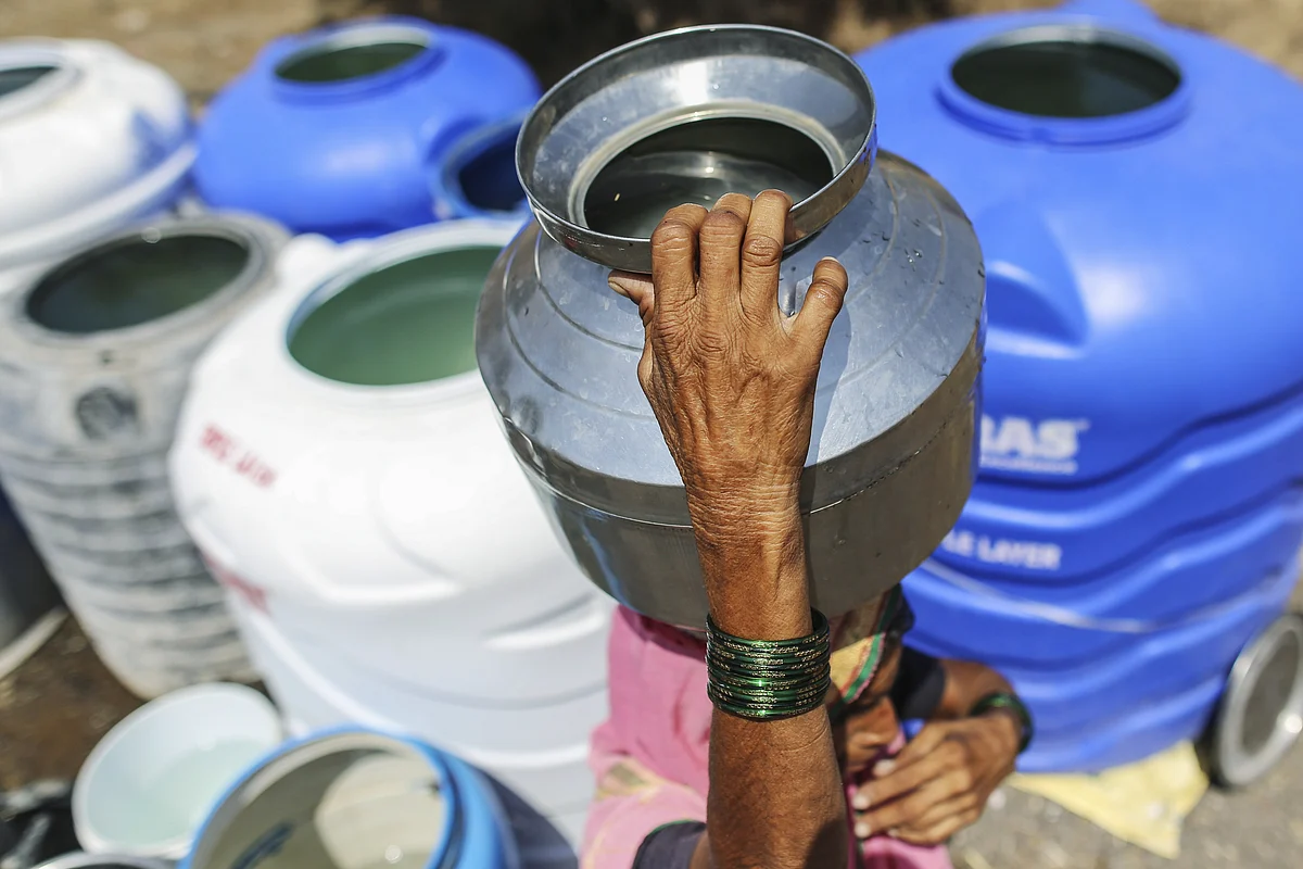 A woman carries a water container on her head filled from public drums at a village in Beed district, Maharashtra.