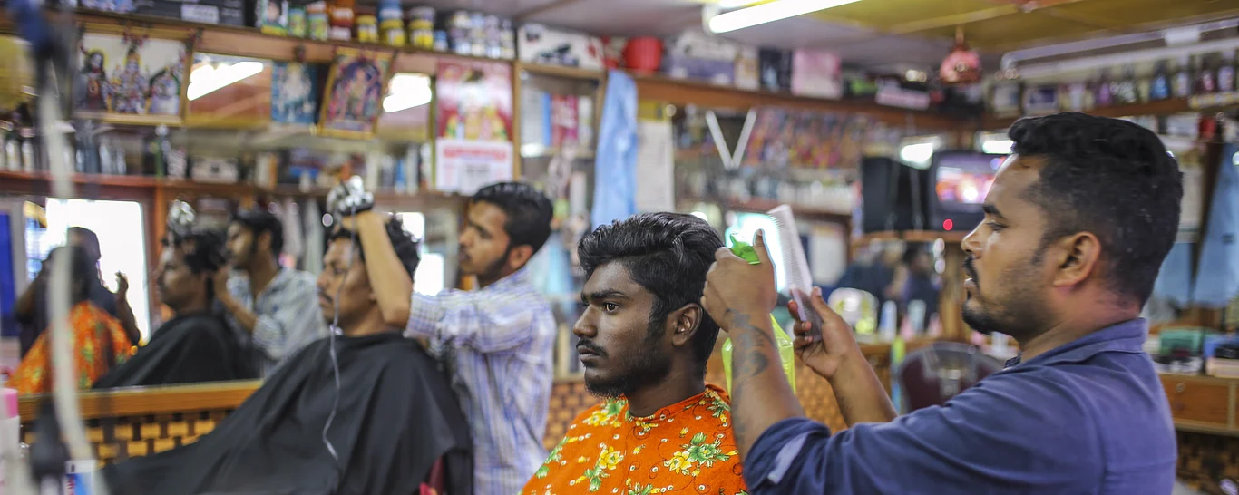 Customers receive haircuts at a barber shop in Coonoor, Tamil Nadu, India, on June 7, 2018. (Photographer: Dhiraj Singh/Bloomberg)
