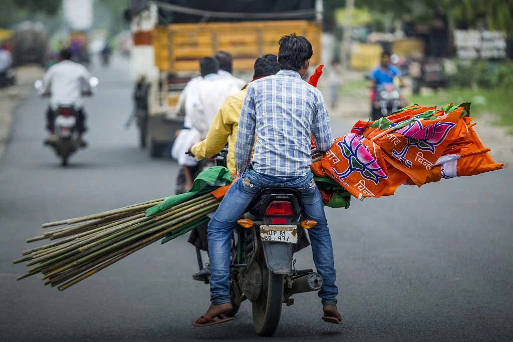 BJP supporters carry the party’s flag during a BJP motorcycle rally. (Photographer: Prashanth Vishwanathan/Bloomberg)