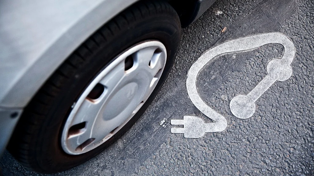 An electrical plug symbol sits on a road surface beside a Autolib’ electric automobile in Paris, France (Photographer: Balint Porneczi/Bloomberg) 