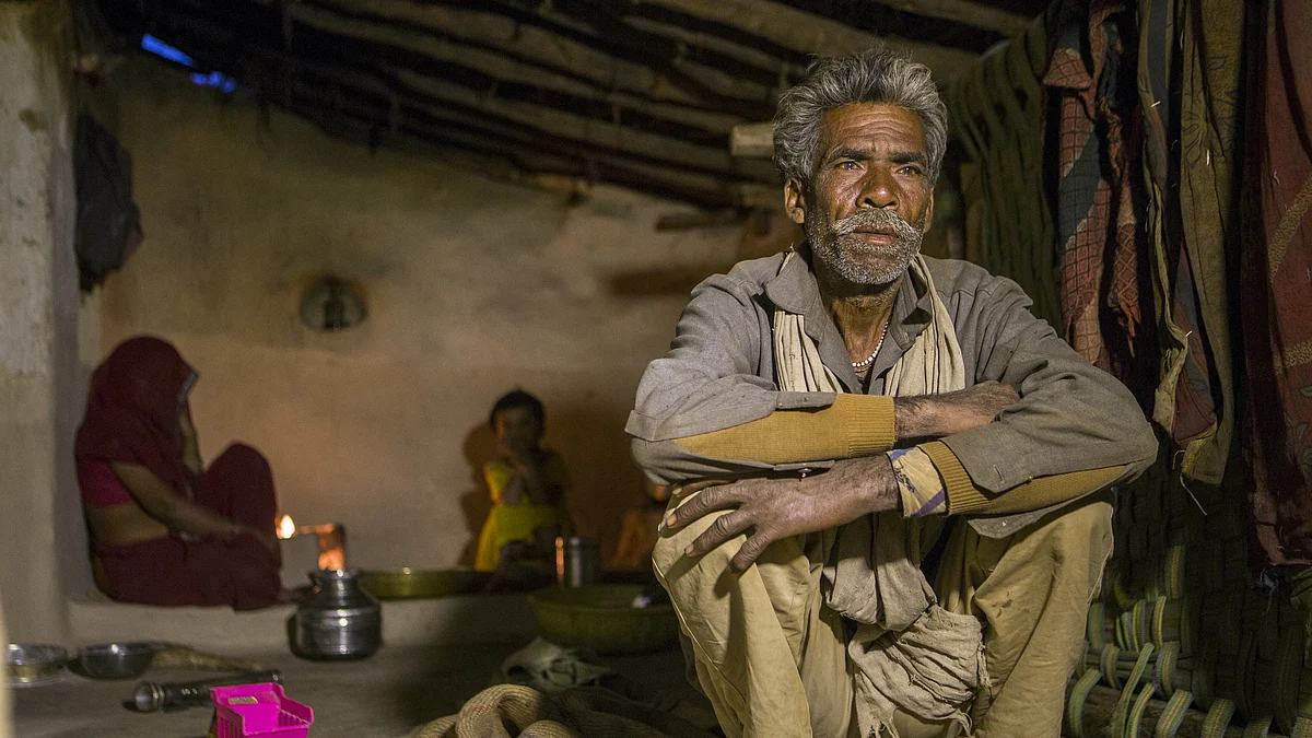 Dharmu Sahariya, 60, right, sits with his family at his home in the village of Sakara in Lalitpur district, Madhya Pradesh, India (Photographer: Prashanth Vishwanathan/Bloomberg)