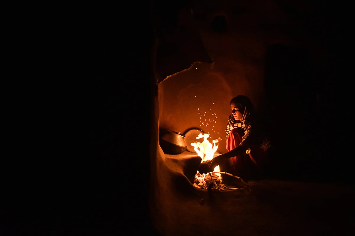 A woman cooks food by fire inside a home in Rajasthan. (Photographer: Anindito Mukherjee/Bloomberg)