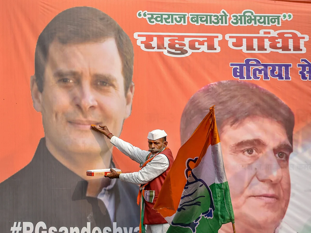 A Congress supporter offers sweets to a photo of Rahul Gandhi, in Lucknow, on Dec. 11, 2018. (Photographer: Nand Kumar/PTI)