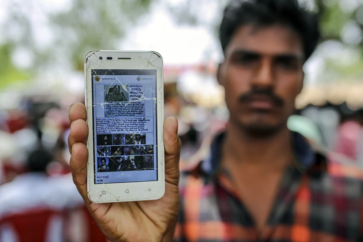 A user holds a mobile phone displaying a fake message shared on WhatsApp in Gadwal, Telangana. (Photographer: Dhiraj Singh/Bloomberg)