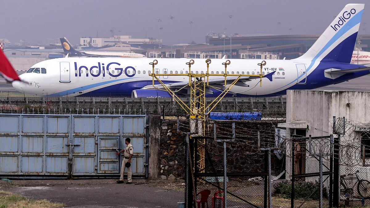 A security guard closes a gate as an Airbus SAS A320 aircraft operated by IndiGo in Mumbai, India. (Photographer: Dhiraj Singh/Bloomberg)