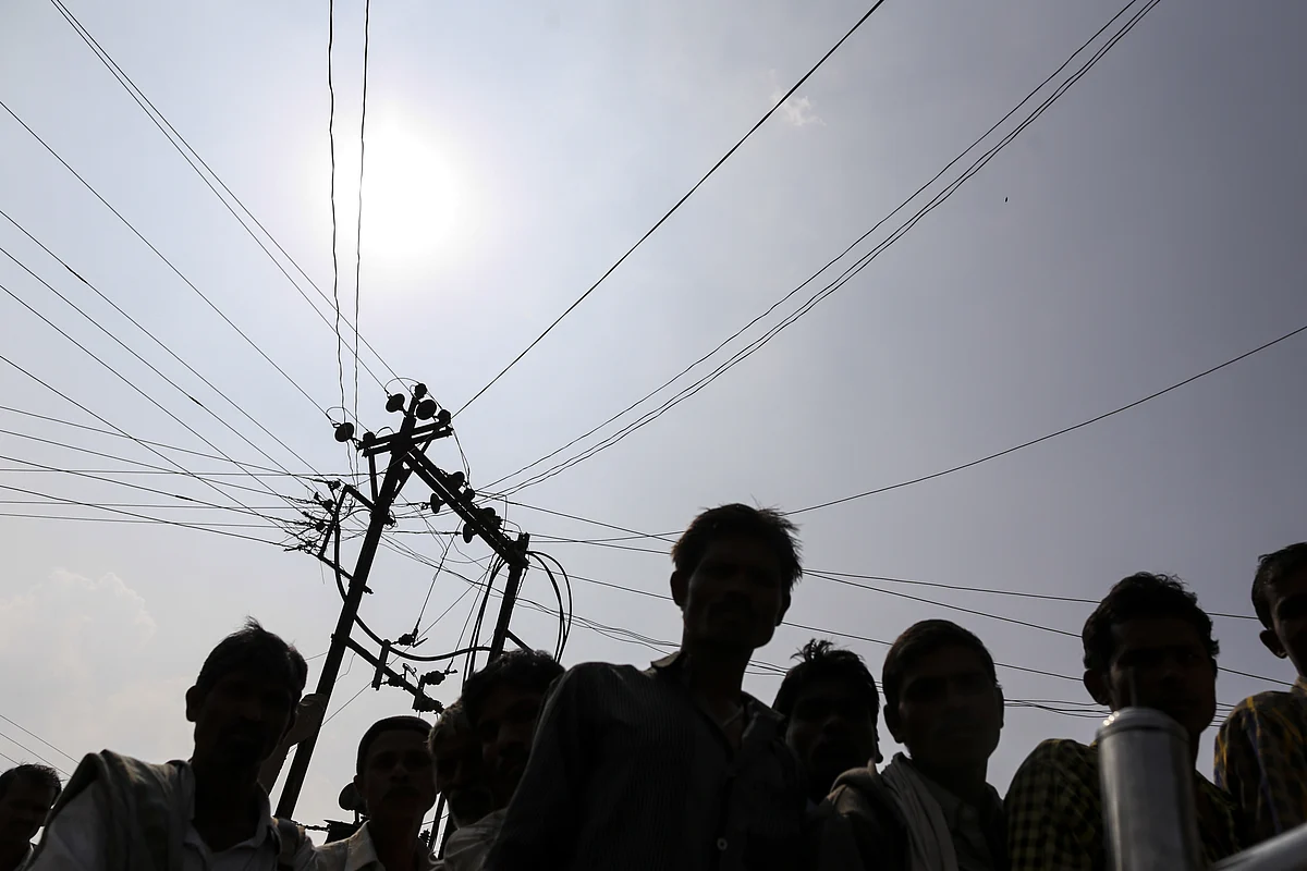 Residents of Dhadgaon village in Maharashtra under an electricity transmission pole and cables. (Photographer: Dhiraj Singh/Bloomberg)