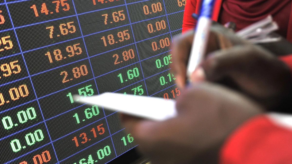 An employee makes notes in front of an electronic stock information screen inside a stock exchange. (Photographer: Riccardo Gangale/Bloomberg)