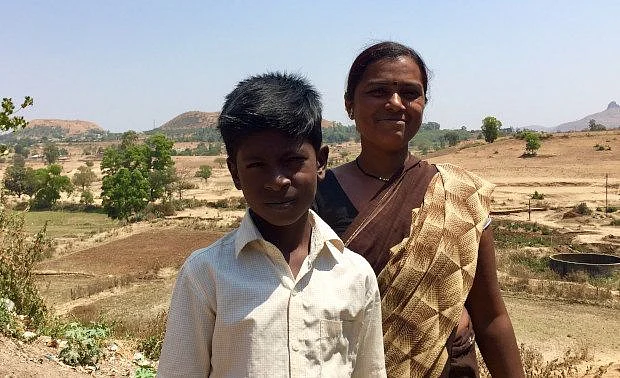 Kamal Gangrude, 35, with her son in Pimplad village of Maharashtra’s northwestern Nashik district. In the backdrop are the fields that used to provide a steady supply of farm jobs, but have now been sold to developers, thus restricting employment options for the village’s poor. (Photographer: Tish Sanghera, IndiaSpend)