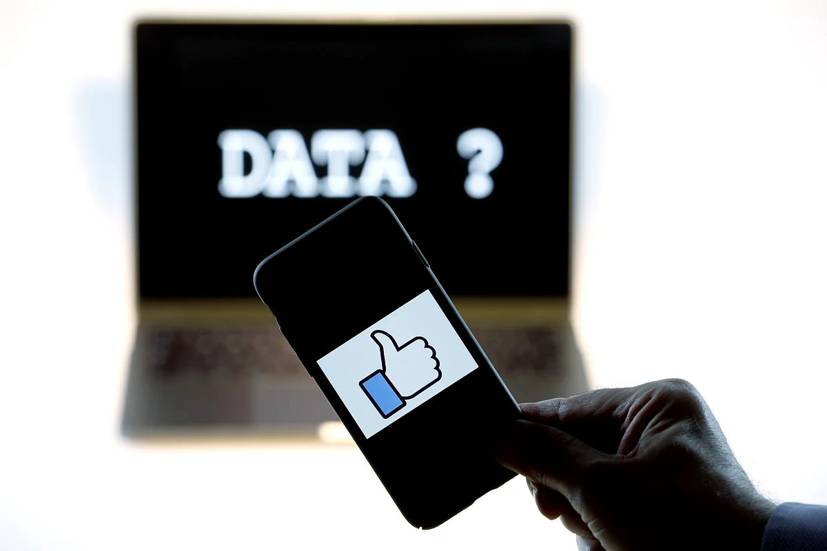 The Facebook thumbs up symbol is shown on an Apple Inc. iPhone against a computer screen. (Photographer: Luke MacGregor/Bloomberg) 