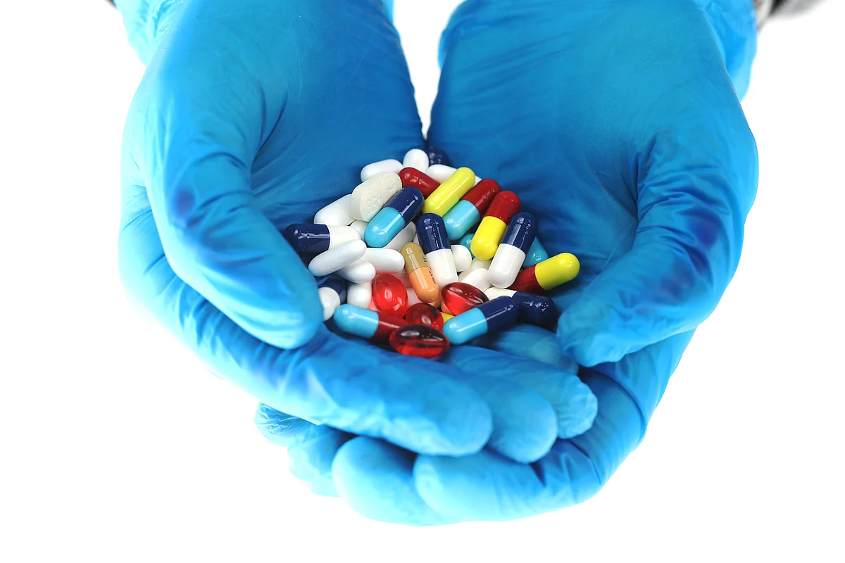<div class="paragraphs"><p> Hands wearing blue surgical gloves hold brightly coloured tablets. (Photographer: Chris Ratcliffe/Bloomberg)</p></div>