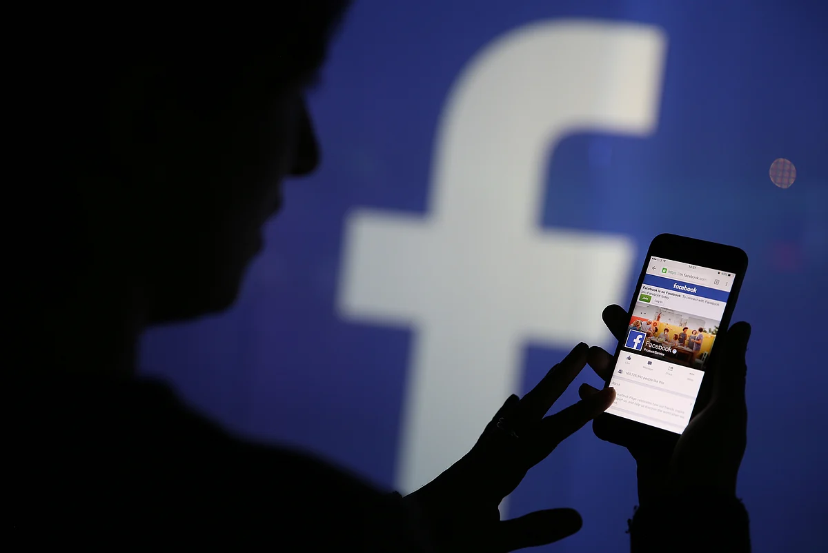 A woman checks the Facebook Inc. site on her smartphone. (Photographer: Chris Ratcliffe/Bloomberg)