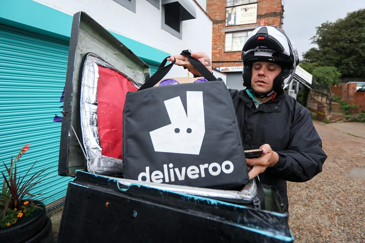 A Deliveroo delivery driver secures an order on his bike from a Deliveroo Editions field kitchen, operated by Roofoods Ltd., in Hove, U.K. (Photographer: Luke MacGregor/Bloomberg)