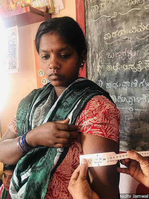 Apart from providing hot meals to pregnant and lactating mothers, Mathrupoorna also focuses on the administration of iron and folic acid tablets, deworming, tetanus injection, gestational weight monitoring and counselling. Here, the <em>anganwadi </em>worker measures a beneficiary’s mid-upper-arm circumference to check for malnutrition.