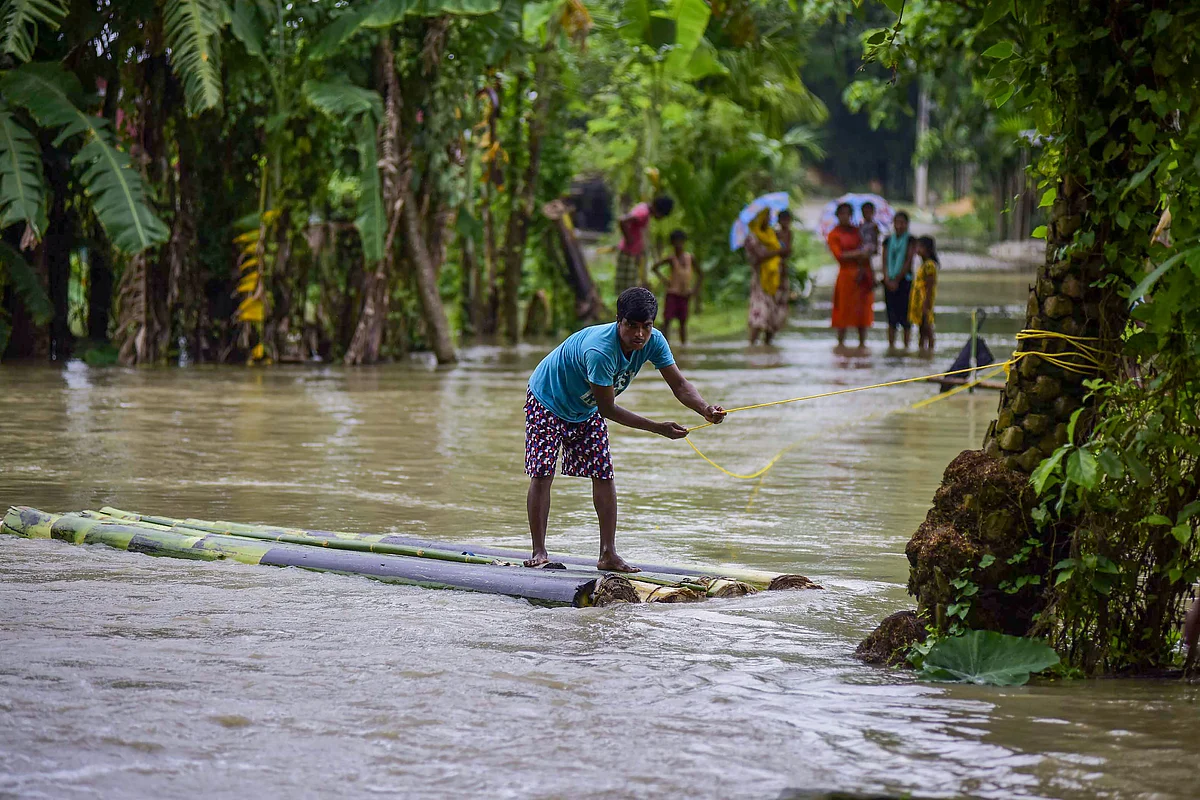 A man rows a makeshift raft to cross floodwaters following incessant monsoon rainfall, at Lahorighat village in Morigaon (Source: PTI)