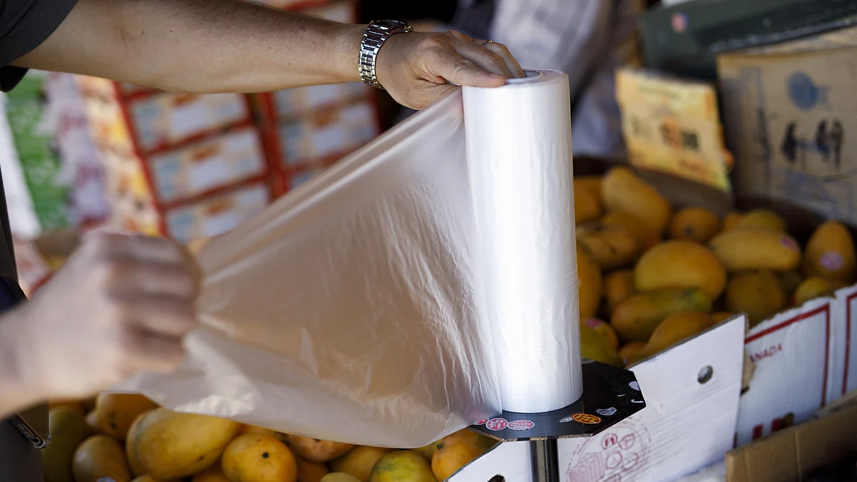 A customer reaches for a plastic bag at a grocery store. (Photographer: Cole Burston/Bloomberg)
