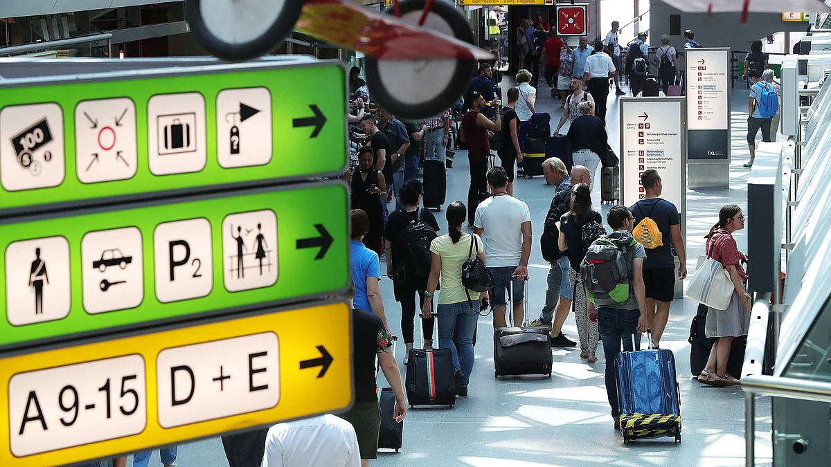 Travelers pull their luggage inside a terminal building at an airport. (Photographer: Krisztian Bocsi/Bloomberg)
