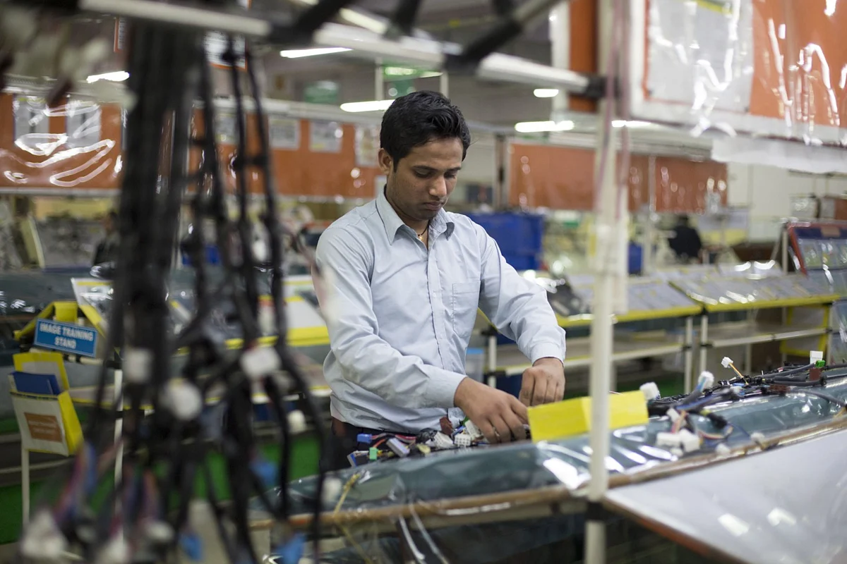 A worker assembles a wire harness at the Motherson Sumi plant in Faridabad. (Photographer: Brent Lewin/Bloomberg)