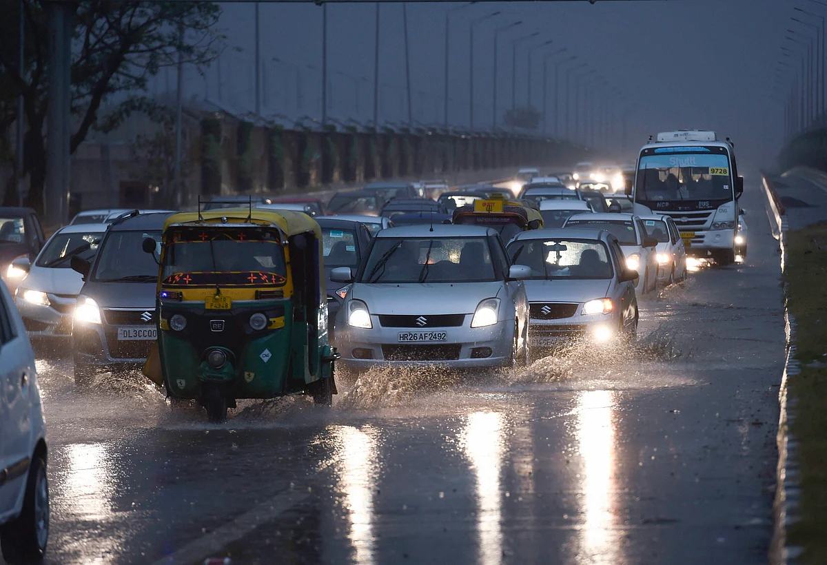 Traffic moves on a street during rains as dark clouds hover over New Delhi. (Photograph: PTI)