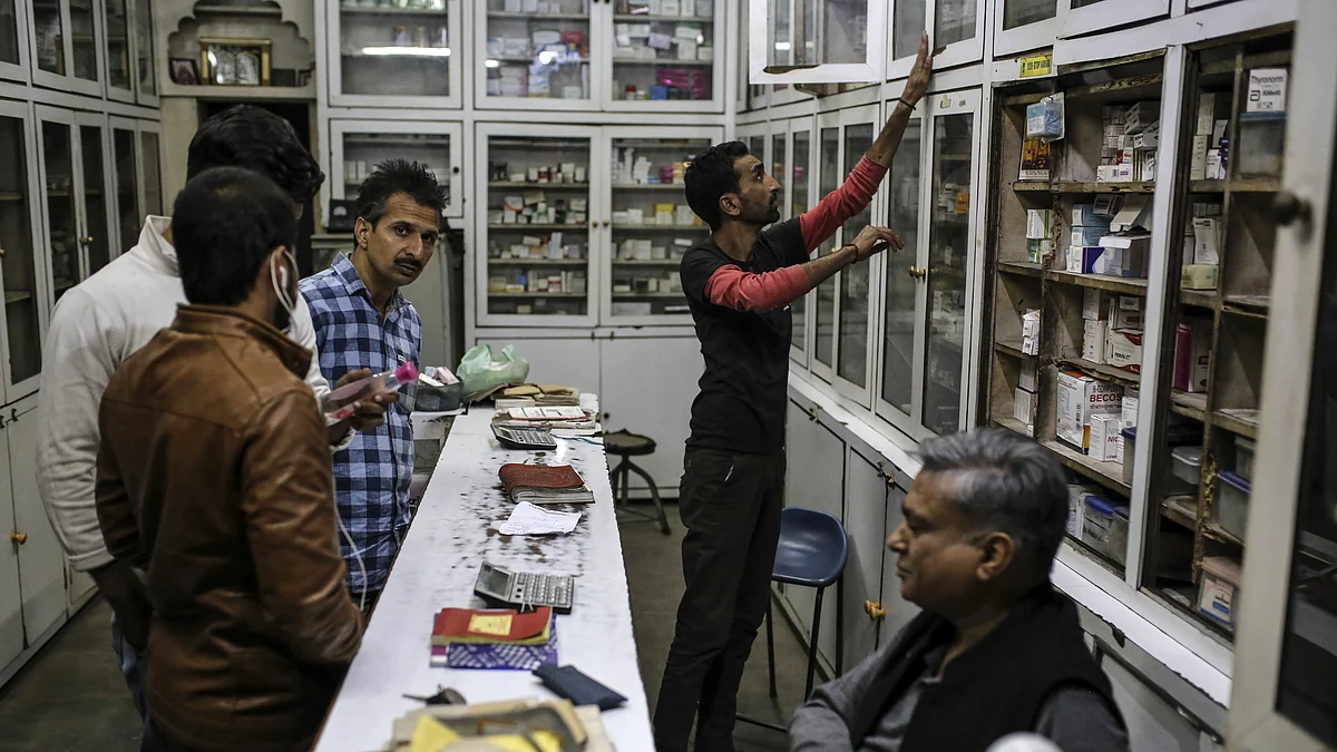 Customers wait as a vendor, right, looks for products at a pharmacy in Raghunath Market at night in Jammu, Jammu and Kashmir, India. (Photographer: Dhiraj Singh/Bloomberg)