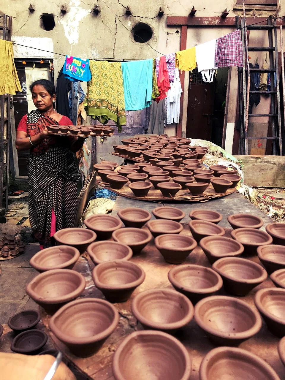 Pramila Parma lays out clay diyas to dry in Dharavi’s Kumbharwada. (Source: BloombergQuint)