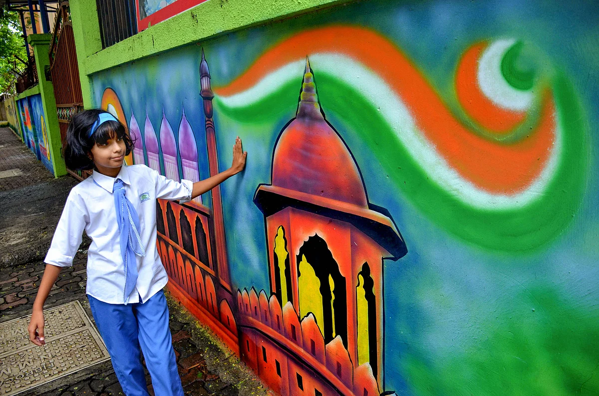 A school student runs her hand on a freshly painted mural on the boundary wall of her school, on Aug. 1, 2019. (Photograph: PTI)