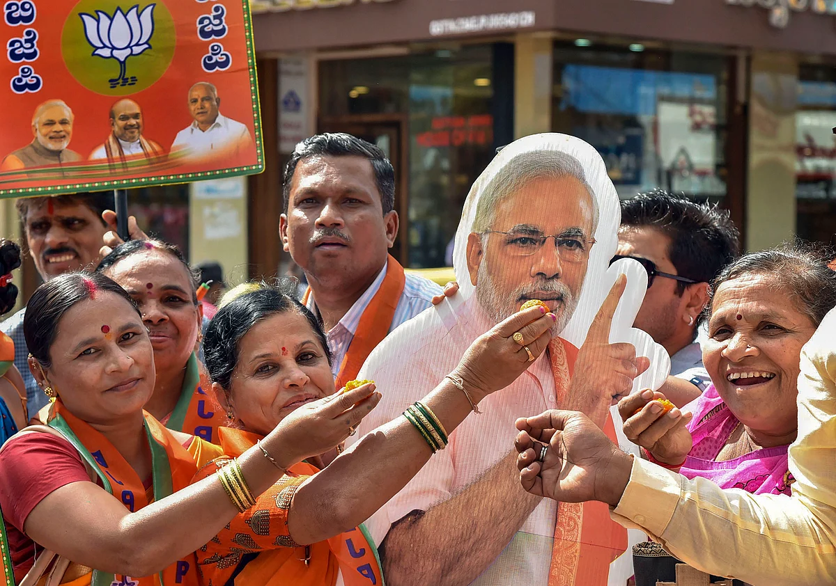 BJP supporters offer sweets to a cut-out of Prime Minister Narendra Modi (Source: PTI)