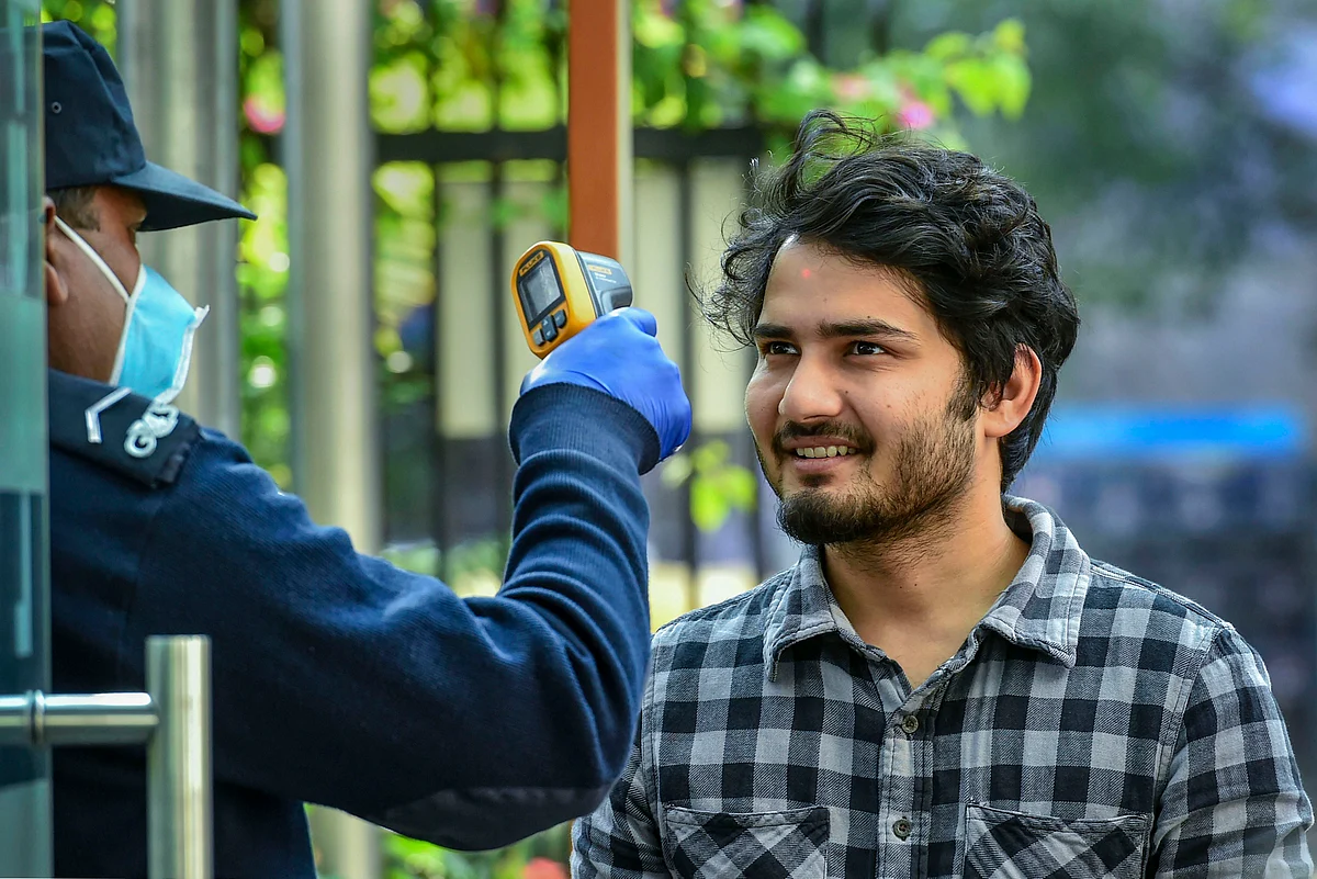 An official uses a thermal screening device on an employee at an office in New Delhi (Source: PTI)