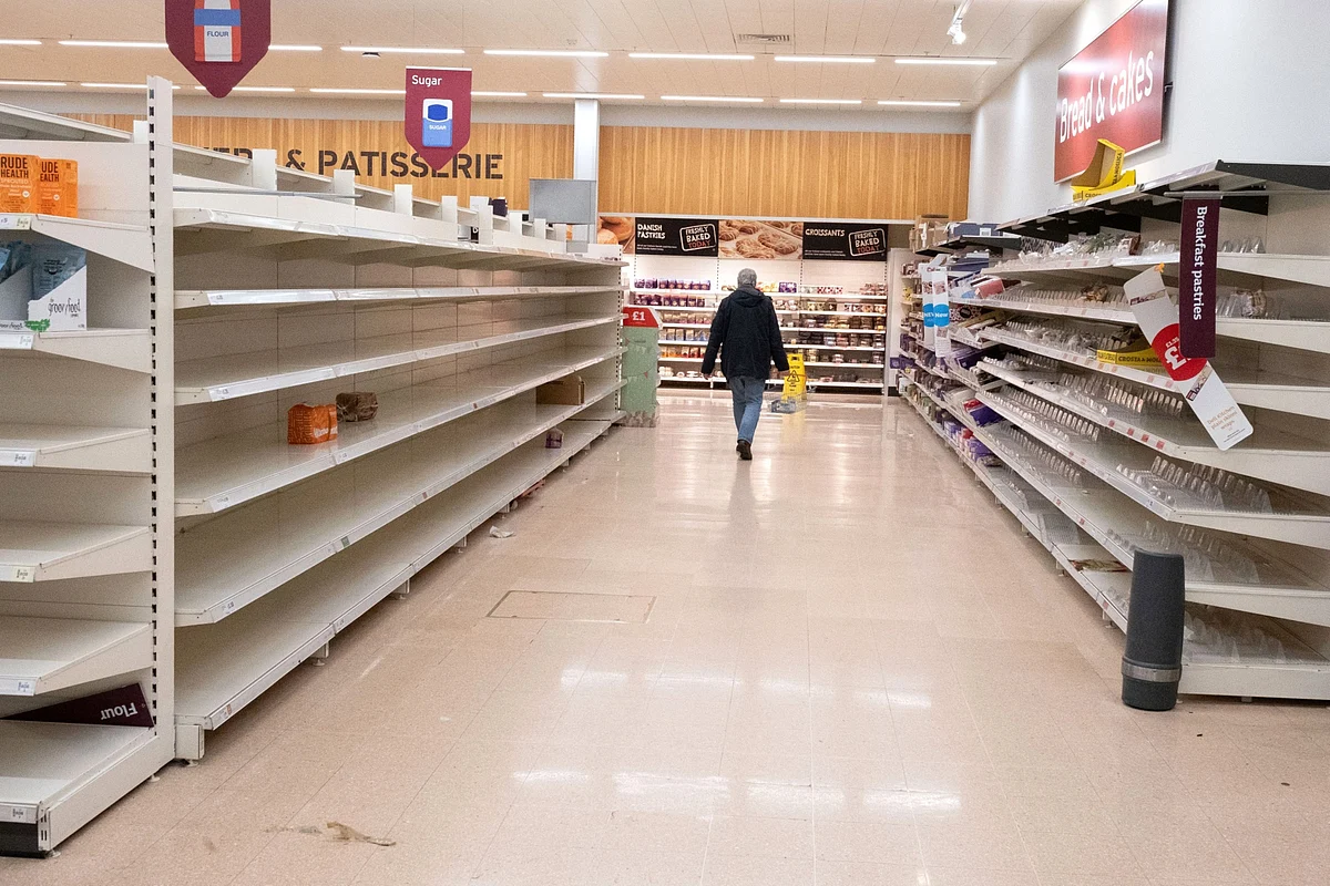 A customer walks past empty shelves after sugar, flour, bread and cakes products sold out in a J Sainsbury Plc supermarket in London, U.K., on Tuesday, March 17, 2020. (Photographer: Bryn Colton/Bloomberg)