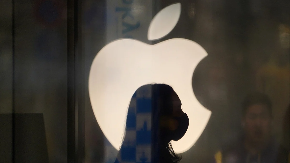 A employee wearing a protective mask is silhouetted while standing in front of an Apple Inc. logo at the company’s store, temporarily closed due to the coronavirus, in the Ginza area of Tokyo, Japan. (Photographer: Toru Hanai/Bloomberg)