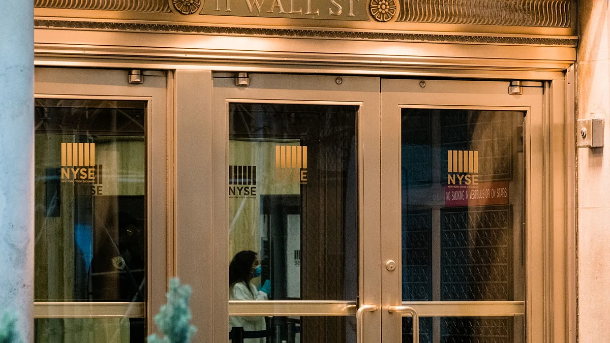 A person wearing a protective mask and gloves stands inside the entrance of the New York Stock Exchange in New York, U.S. (Photographer: Gabriela Bhaskar/Bloomberg)