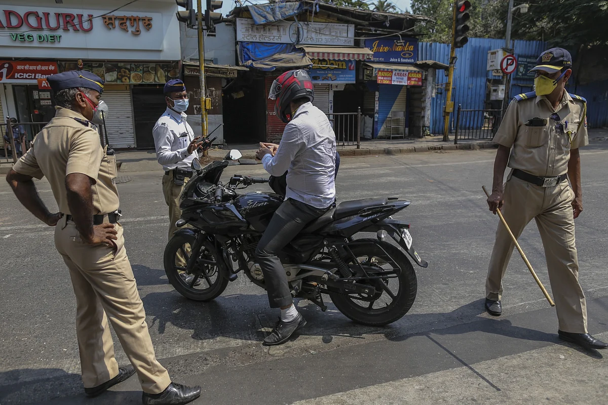 Police officers wearing protective face masks stop motorcyclist during a curfew in Mumbai, India. (Photographer: Dhiraj Singh/Bloomberg)