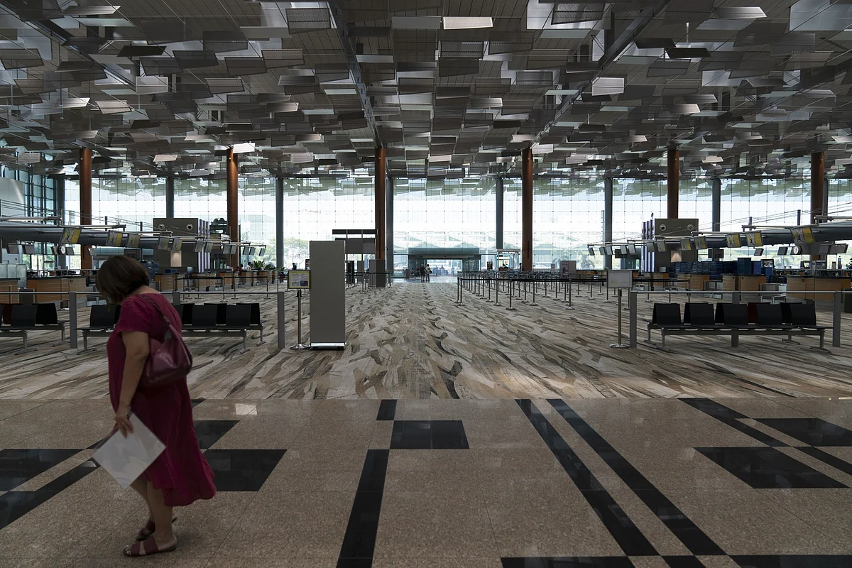 A woman walks past an empty check-in area in Terminal 3 at Singapore Changi Airport in Singapore, on Tuesday, March 17, 2020. All arrivals to Singapore from the Asean group of nations as well as Japan, Switzerland and U.K. will have to self-isolate for two weeks in the city-state’s latest measure to tackle the coronavirus pandemic. (Photographer: Wei Leng Tay/Bloomberg)