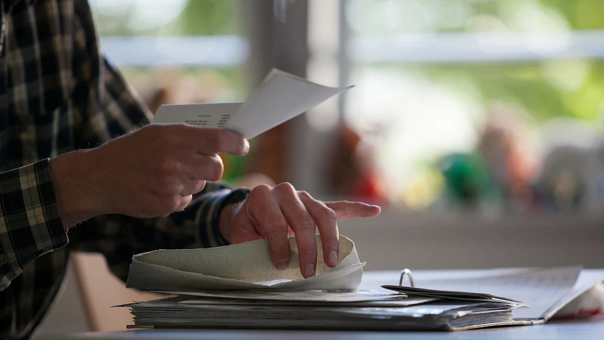 A visitor holds paper work and checks documents. (Photographer: Krisztian Bocsi/Bloomberg)