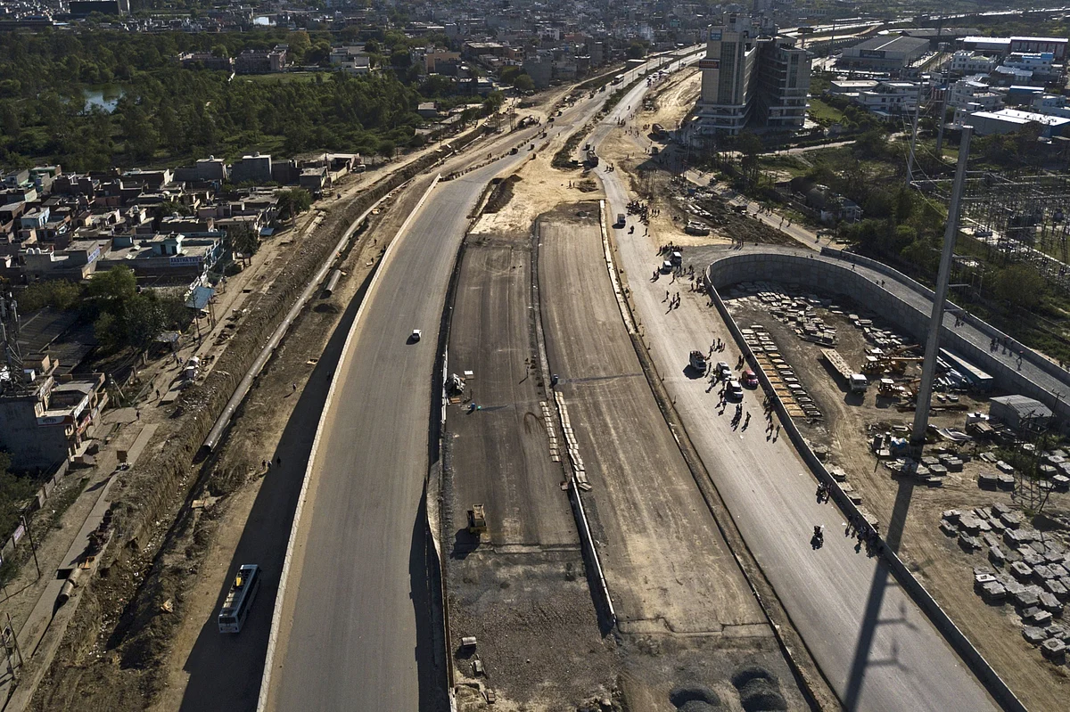 Vehicles travel past migrant workers and their families walking along a near deserted highway during a lockdown imposed due to the coronavirus in New Delhi, India. (Photographer: Anindito Mukherjee/Bloomberg)