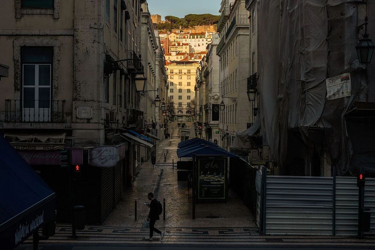 A pedestrian crosses a deserted street of usually crowded shops and cafes on March 22. (Photographer: Jose Sarmento Matos/Bloomberg) 