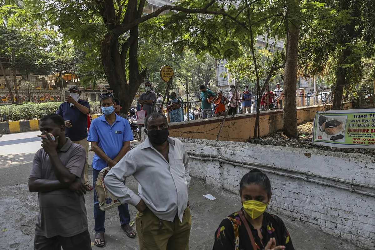 Customers wearing protective face masks form a queue for supplies outside supermarket in Mumbai, India. (Photographer: Dhiraj Singh/Bloomberg)