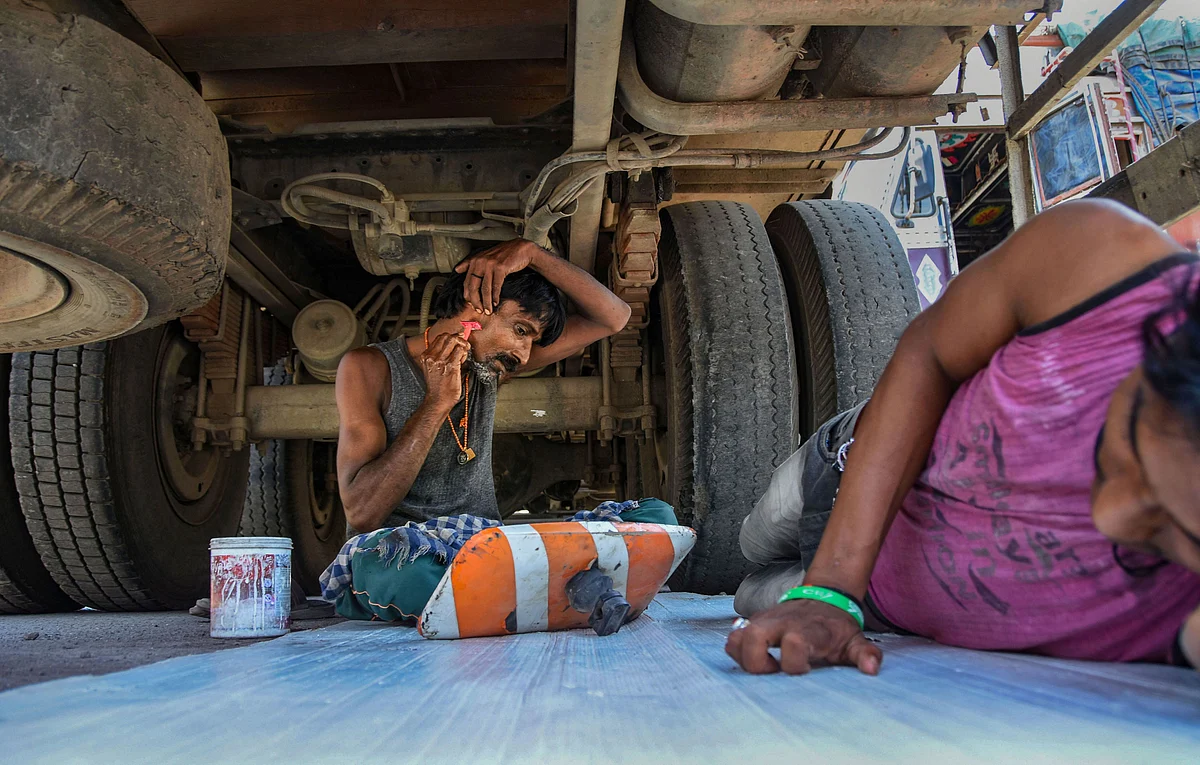 A truck driver shaves his beard underneath his truck in Mumbai, during a government-imposed nationwide lockdown, on April 6, 2020. (Source: PTI)
