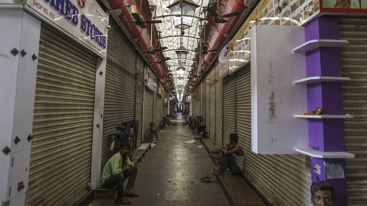People sit outside shuttered stores at Crawford Market in Mumbai, on March 25, 2020. (Photographer: Dhiraj Singh/Bloomberg)