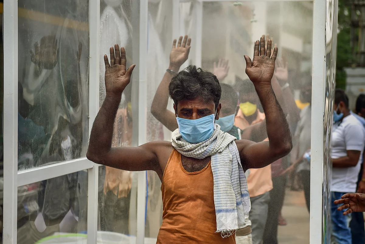 Labourers pass through a disinfectant tunnel in Bengaluru, on April 9, 2020. (Photograph: PTI)