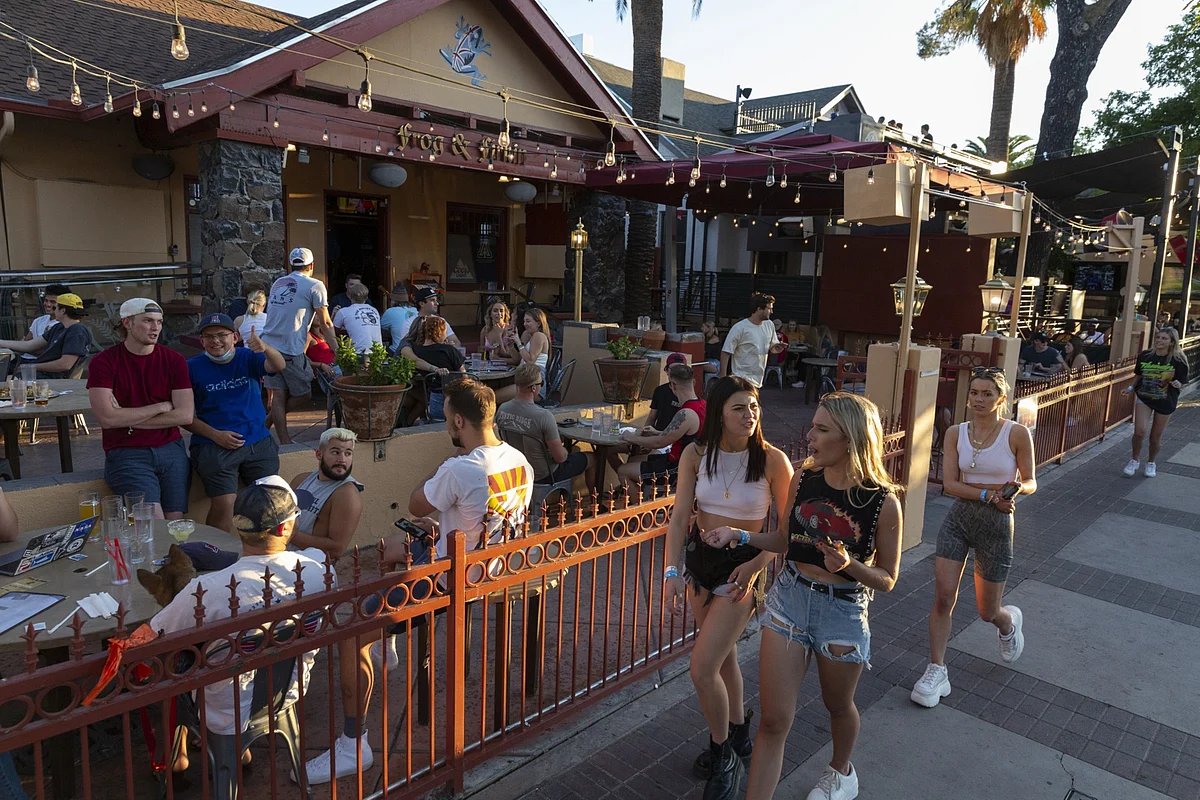 Pedestrians walk past customers sitting outside at a bar in Tucson, Arizona, on May 11, 2020. (Photographer: Cheney Orr/Bloomberg)