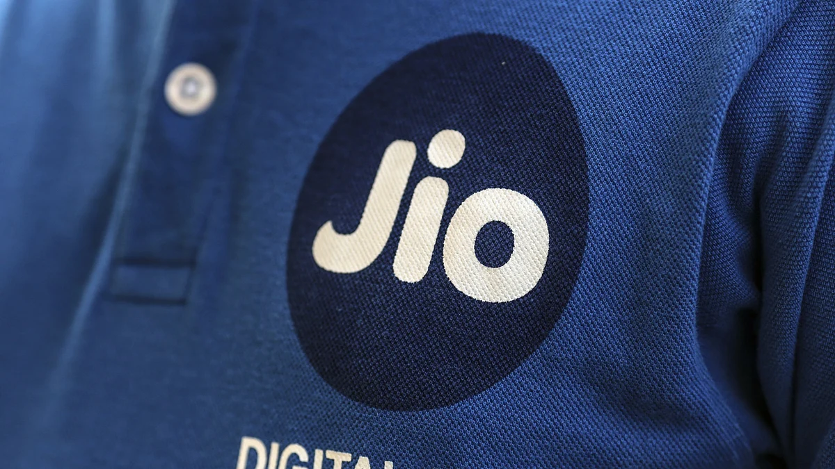 The logo of Reliance Jio, the mobile network of Reliance Industries Ltd., is seen on an employees shirt as he stands for a photograph outside a store in Mumbai. (Photographer: Dhiraj Singh/BloombergTopics)