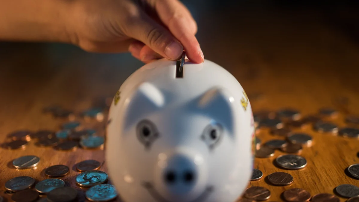 A coin is dropped into a piggy bank in this arranged photograph. (Photographer Ron Antonelli/Bloomberg)